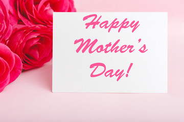 Happy Mothers Day text on gift card in flower bouquet of pink roses on pink background. Greeting card for Mom. Flower delivery, Congratulations card in flowers for women. Greeting card in roses