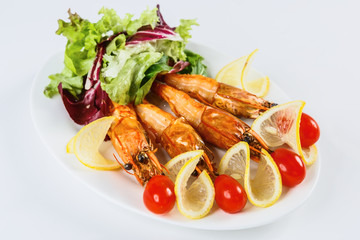 Shrimps, tomatoes and lemon are beautifully laid out on a platter.