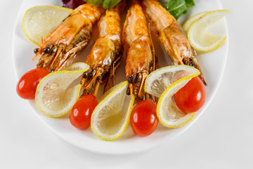 Shrimps, tomatoes and lemon are beautifully laid out on a platter.