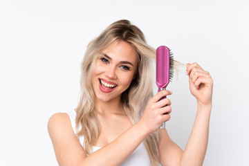 Teenager blonde girl over isolated white background with hair comb and singing