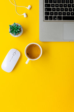 Vertical flat lay minimal home office yellow workspace. Silver laptop and cup of tea. Top view work at home concept