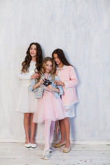 Fototapeta na wymiar Three beautiful fashionable girls in white pink clothes are photographed