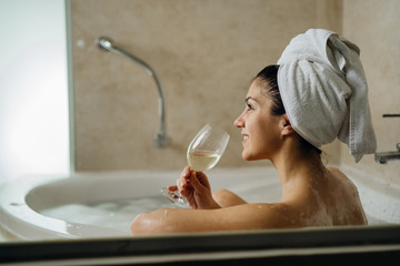 Woman relaxing at home in the hot tub bath ritual,drinking wine.Relaxing spa night in bathroom.Good...