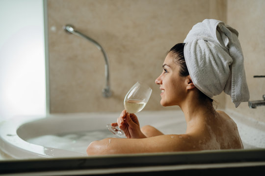 Woman relaxing at home in the hot tub bath ritual,drinking wine.Relaxing spa night in bathroom.Good personal hygiene routine.Skin,body care,aromatherapy.Bath essential oils.Stress relief after work