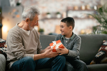 Grandfather giving gift to grandson.	