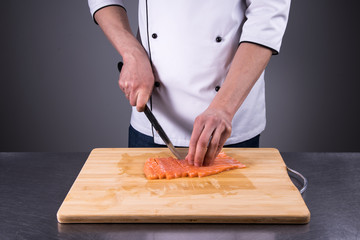 Obraz na płótnie Canvas chef cuts salmon for fresh sushi in a restaurant kitchen8