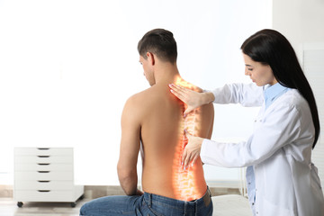Professional orthopedist examining man in medical office. Spinal pain