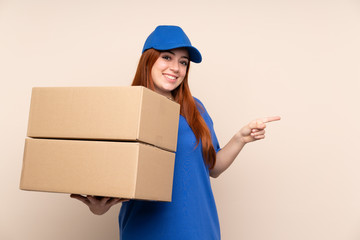 Young teenager delivery girl over isolated background pointing finger to the side