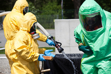 Two men in protective gear decontaminating another man. Virus contamination or chemical or...