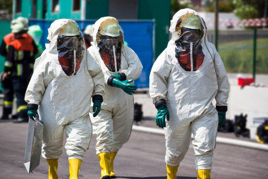 Three men in protective gear disinfecting contaminated areas or cleaning up after chemical or radiation accident. The inflatable gear protects against contamination with viruses, radioactive particles