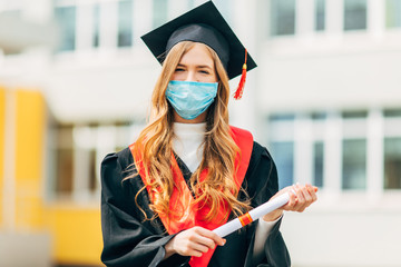 A graduate student in a medical mask, in a black graduation dress, with a diploma in her hands....