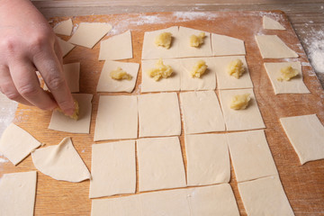 Female hands sculpt dumplings made of dough with potatoes. Cooking at home.