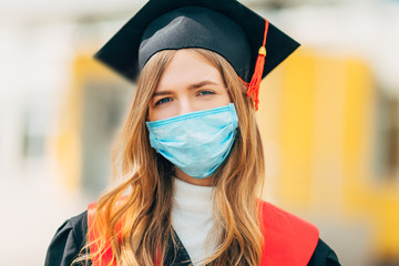 A female graduate student in a medical mask, in a black graduation dress. Graduation ceremony...