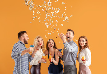 Happy people with confetti and cocktails on color background