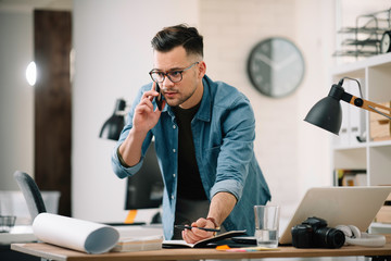 Businessman in office. Handsome man talking on phone at work