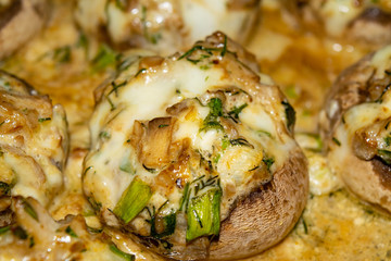 Mushrooms baked in the oven with cheese, green onions and dill. Close up.