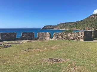 Antigua coastline and outer fort wall with cannon ports as seen from the Fort Berkeley Peninsula in Antigua and Barbuda, Caribbean, Lesser Antilles, West Indies with blue sky copy space.