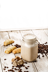 Authentic milkshake in a small jar with nice table presentation of coffee beans and pastry on white wooden table. Picture best use for magazine or casual dine in menu concept.