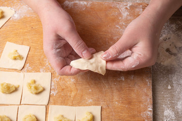 Female hands sculpt dumplings made of dough with potatoes. Cooking at home.