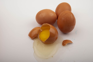 A broken chicken egg and scattered eggs on a white background. Close up.