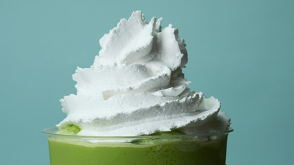 Whipping cream on Iced tea fresh milk take home cup beverage for summer isolated on blue background.