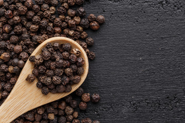 Peppercorn background. Dry black pepper seeds. Top view.On a black background. free space for your text.