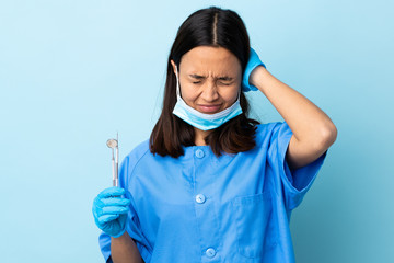 Young brunette mixed race dentist woman holding tools over isolated background frustrated and...