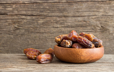 Dates, tasty dry fruit in burlap sack or bowl on wooden rustic background, ramadan kareem food, copy space selective focus (Phoenix dactylifera )