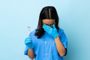 Young brunette mixed race dentist woman holding tools over isolated background with tired and sick expression