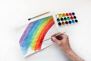 a rainbow is painted by a teenager's hand on a white background