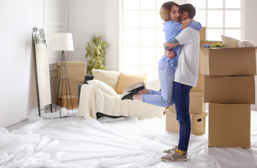 Happy couple moving house, boxes around, holding keys