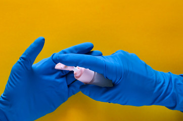 Hands in a blue medical glove with an antibacterial disinfectant - hand sanitizer. Antiseptic protects against viral, airborne diseases. Coronavirus, covid-19 healthcare concept, copy space.