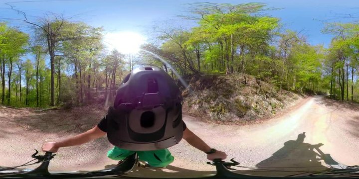 VR360 Riding a mountain bike on a gravel road through the sunny forest