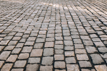 The gray paving stones close up. The texture of the old dark stone. Vintage, grunge. Road surface.