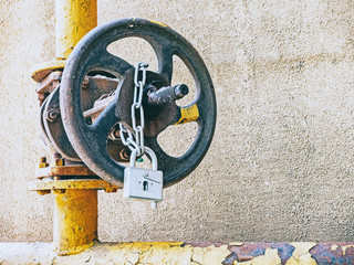 Round water valve with lock and chain on a yellow pipe