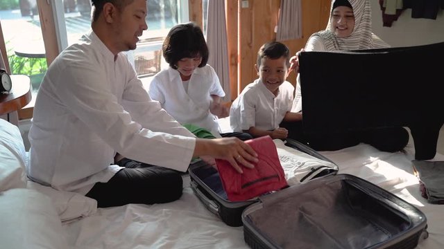 asian family prepare clothes and put in suitcase for carried when mudik go to back village home