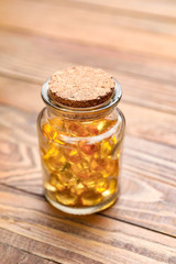 Jar with fish oil capsules on wooden background