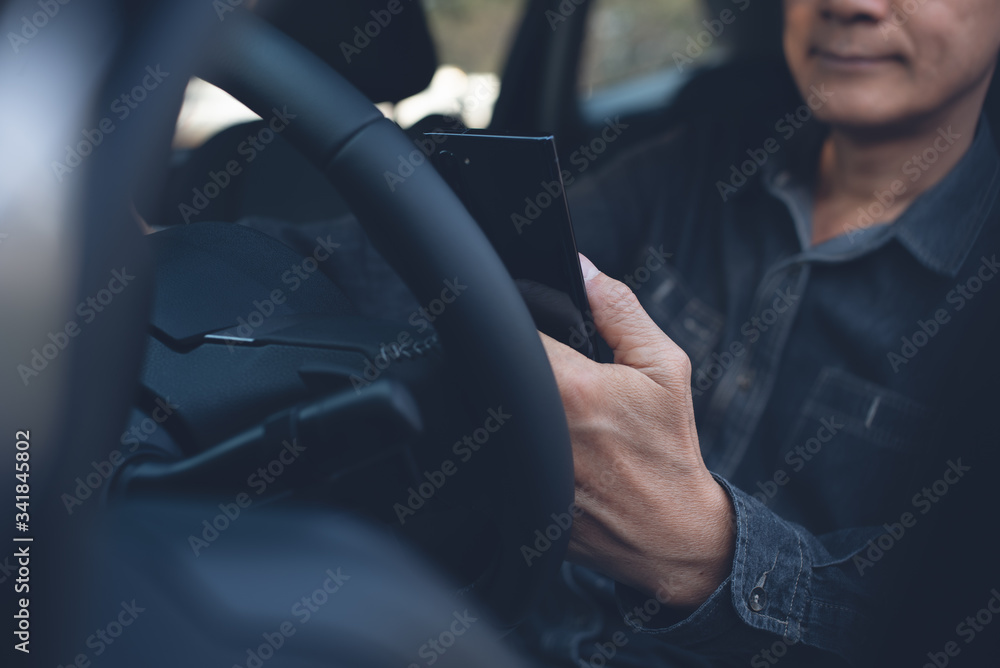 Poster man using smartphone inside car