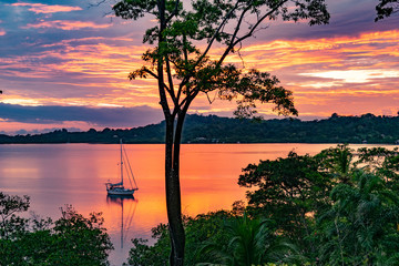 Obraz na płótnie Canvas Sailboat anchored during a sunset in the tranquil Dolphin Bay, Panama