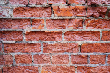 Decorative wall of destroyed red brick covered with varnish. Background for design on a construction or architectural theme.