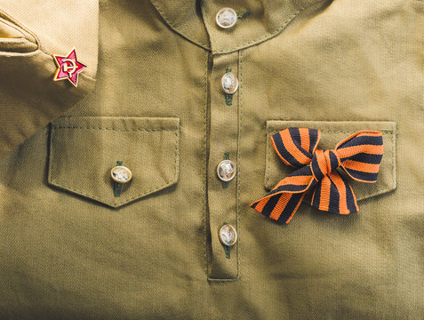 Holiday of 9 May Victory day 1945 background. Soviet army military uniform of tunic, forage cap, St. George ribbon. Flat lay, layout, top view, copy space.