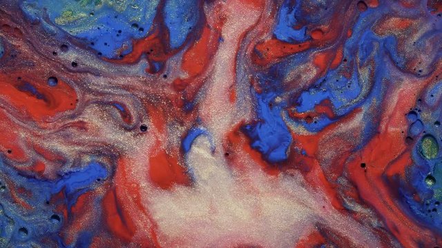 Colorful gold dust blue and red paint flow on silver and universe colors surface mix in fantastic design and patterns. Sparkling particles, ink drops and mixing. Multicolored background in motion