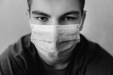 Close - up portrait of a man with a gaze and in wearing medical mask. Protection against virus, infection, exhaust and industrial emissions. Monochrome studio shot.