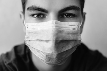 Close - up portrait of man wearing medical mask. Protection against virus, infection, exhaust and industrial emissions. Ambulance services and treatment concept. Monochrome studio shot.