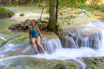 Traveler in blue swimsuit beautiful relax at  Erawan Waterfall