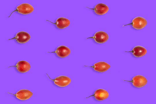 Fruit pattern of raw tomarillo or tomate de &aacute;rbol on violet background from top view