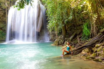 Woman in blue swimsuit sit at  Erawan Waterfall and natural