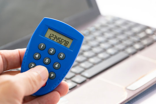 Close up of a hand holding a secure remote access and authentication, one-time safe password, internet banking token and computer 