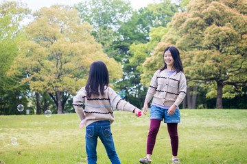 Fototapeta premium 公園でしゃぼん玉を遊んでいる子供姉妹