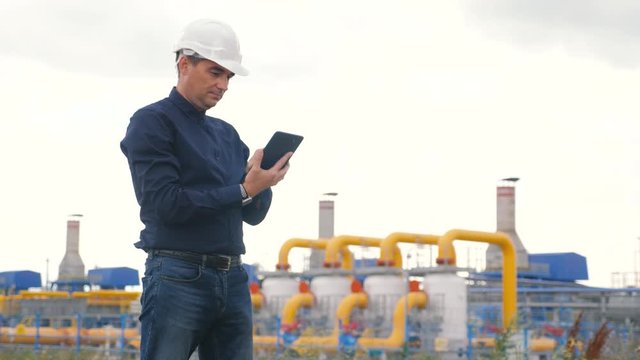 engineer man power and energy using digital tablet. worker in a helmet works at an oil-gas plant. engineer studies documents lifestyle business industry